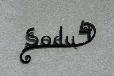 a metal sign on the side of a wall at Dvi liepos in Merkinė