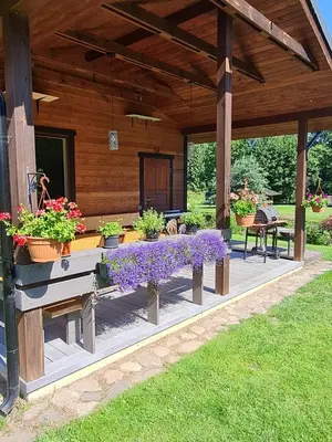 a porch of a house with purple flowers on it at Atostogų namelis-pirtis Prie upės in Anykščiai