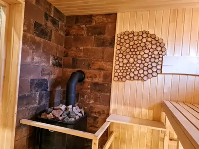 a sauna with a wood burning stove in it at Atostogų namelis-pirtis Prie upės in Anykščiai