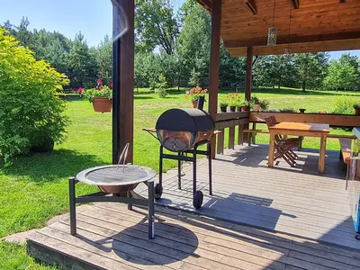 a grill and a table on a wooden deck at Atostogų namelis-pirtis Prie upės in Anykščiai
