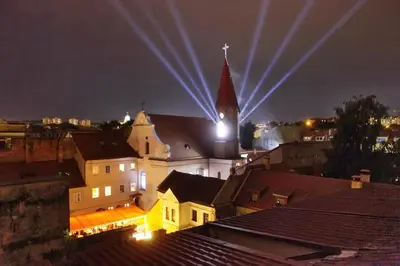 a church with a steeple and a clock tower at night at Medieval Super Studio in Vilnius