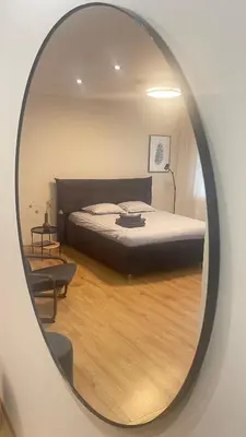 a mirror reflecting a bedroom with a bed in a room at S&A apartamentai in Panevėžys