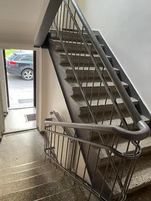 a metal staircase in a building with a car in a parking lot at S&A apartamentai in Panevėžys