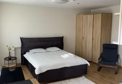 a bedroom with a large bed and a blue chair at S&A apartamentai in Panevėžys