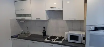 a kitchen with white cabinets and a stove and a microwave at Butukas in Anykščiai