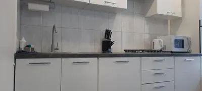 a kitchen with white cabinets and a white microwave at Butukas in Anykščiai