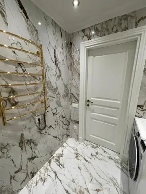 a white bathroom with a door and marble walls at ART Uzupis Apartment in City center in Vilnius