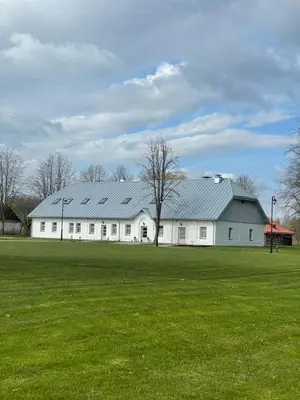 a large white barn with a large green field at A. Smetonos Dvaro Smetonienės svetainė in Lėnas
