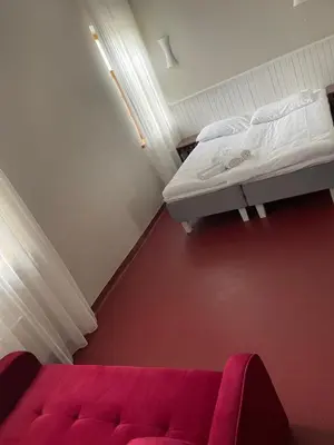 a small room with a bed and a red couch at A. Smetonos Dvaro Smetonienės svetainė in Lėnas