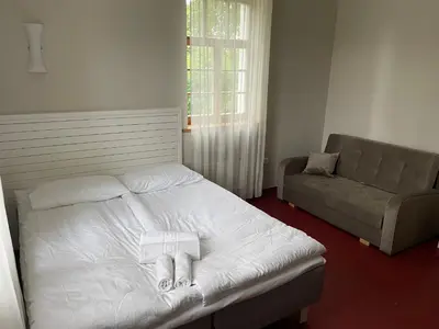a bedroom with a white bed and a couch at A. Smetonos Dvaro Smetonienės svetainė in Lėnas