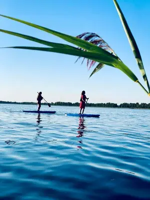 two people on paddle boards in the water at A. Smetonos Dvaro Smetonienės svetainė in Lėnas