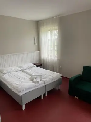 a bedroom with a white bed and a green chair at A. Smetonos Dvaro Smetonienės svetainė in Lėnas