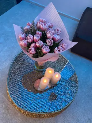 a vase of pink flowers and candles on a table at Luxury Queen V apartment with Jacuzzi in Kaunas