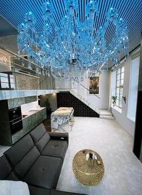 a living room with a couch and a blue chandelier at Luxury Queen V apartment with Jacuzzi in Kaunas