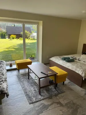 a bedroom with a bed and a table and a window at Pušynas1 in Anykščiai
