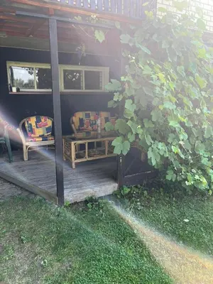 a porch with a couch and a chair on a deck at Pušynas1 in Anykščiai