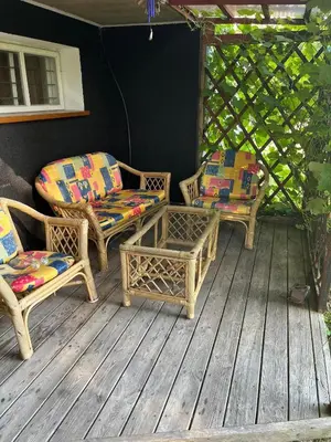 three wicker chairs and a table on a porch at Pušynas1 in Anykščiai