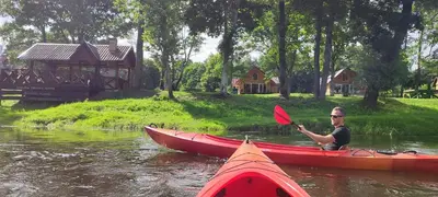 a man in a kayak on the water with a red paddle at Sodyba Žaliasis slėnis Anykščiuose in Anykščiai