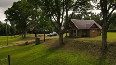 a house with a solar roof on a yard with trees at Sodyba Žaliasis slėnis Anykščiuose in Anykščiai