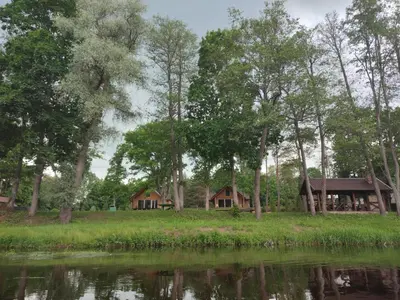 a couple of cottages next to a body of water at Sodyba Žaliasis slėnis Anykščiuose in Anykščiai