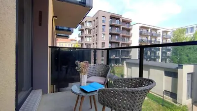 a balcony with two chairs and a table with a vase of flowers at Brand New Mindaugas Luxury Designer Apart in Vilnius