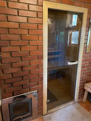 a brick wall with a glass door next to a fireplace at Vila Paradise Bay in Smalvos