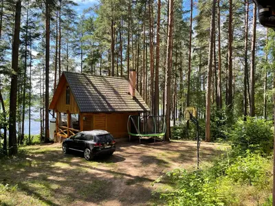 a car parked in front of a cabin in the woods at Vila Paradise Bay in Smalvos