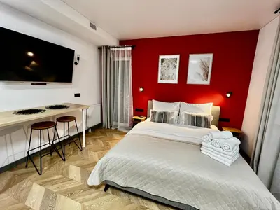 a bedroom with a red wall with a bed and a desk at Salt Garden Apartments in Druskininkai