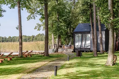 a cabin in the woods with benches and trees at Paplūdimio namukas in Molėtai