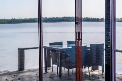 a table and chairs on a dock with a view of the water at Paplūdimio namukas in Molėtai