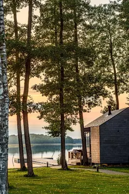 a cabin in the woods next to a lake with trees at Paplūdimio namukas in Molėtai