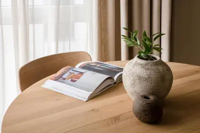 a vase on a table with a book and a plant at #stayhere - Brand New Unique Designer 1BDR in Trendy Neighbourhood in Vilnius