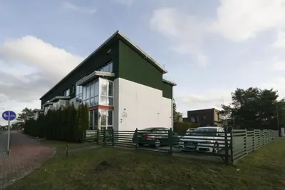 a green and white house with a car parked in front at Apartamentai Aqua in Druskininkai