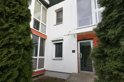 a white house with a door next to a hedge at Apartamentai Aqua in Druskininkai