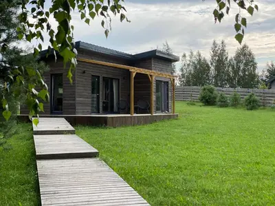 a small house in a yard with a green field at Pineplace in Joniškis