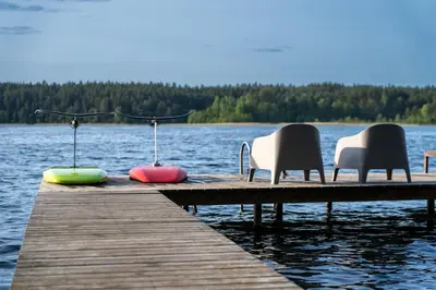 a group of chairs sitting on a dock on a lake at Viesuliškės Lakeside Glamping in Lakaja