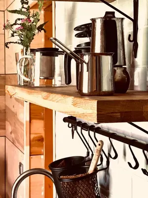 a kitchen counter with pots and pans on a shelf at Viesuliškės Lakeside Glamping in Lakaja