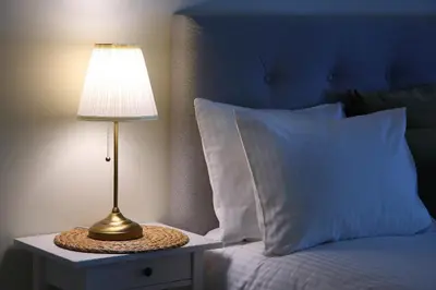 a lamp on a night stand next to a bed at Taurakalnis apartment in Vilnius