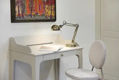a white desk with a lamp and a chair at Taurakalnis apartment in Vilnius