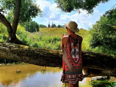 a man wearing a hat standing next to a river at Gluosnių vila - Adutiškio pirtis in Švenčionys