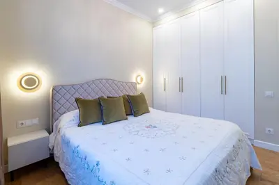 a white bedroom with a large bed with green pillows at Luxury Central Apartment in Putvinskio street in Kaunas