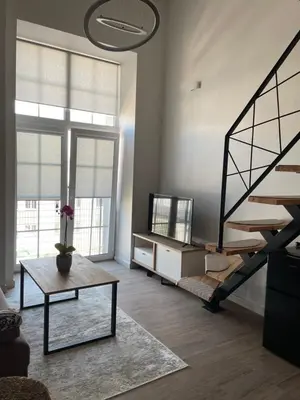 a living room with a spiral staircase and a table at Radio city loft in Kaunas