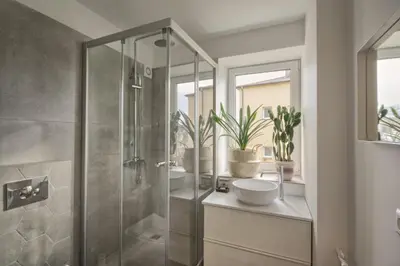 a bathroom with a shower with two sinks and two mirrors at Modern and cozy flat in Druskininkai