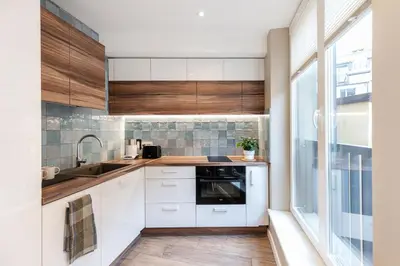 a kitchen with white cabinets and a sink and a window at Vingriu Street Apartment by Reside Baltic in Vilnius