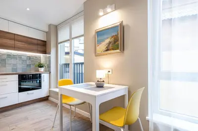 a kitchen with a white table and yellow chairs at Vingriu Street Apartment by Reside Baltic in Vilnius