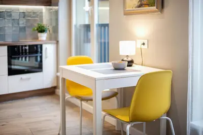 a kitchen with a white table and yellow chairs at Vingriu Street Apartment by Reside Baltic in Vilnius