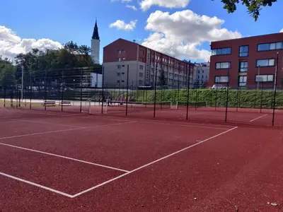 a tennis court in front of a building at Centrinio parko apartamentai in Šiauliai