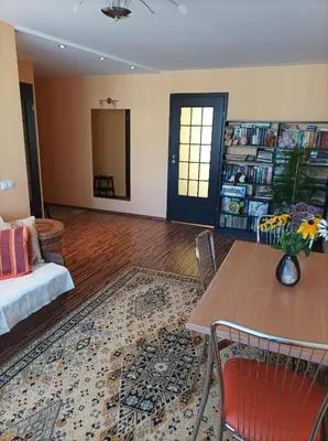 a living room with a bed and a table and a book shelf at Centrinio parko apartamentai in Šiauliai