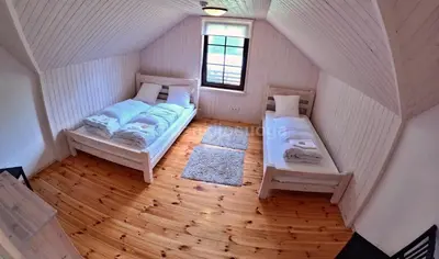 an attic room with two beds and a window at Dzūkijos uoga in Viršurodukis