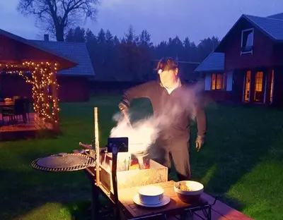 a man standing next to a table with a grill at Dzūkijos uoga in Viršurodukis